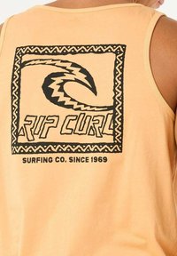Oranges Tanktop mit schwarzem Grafikdesign, das den Text "RIP CURL" und eine Wellenform zeigt, umrahmt von einem gemusterten Rahmen.
