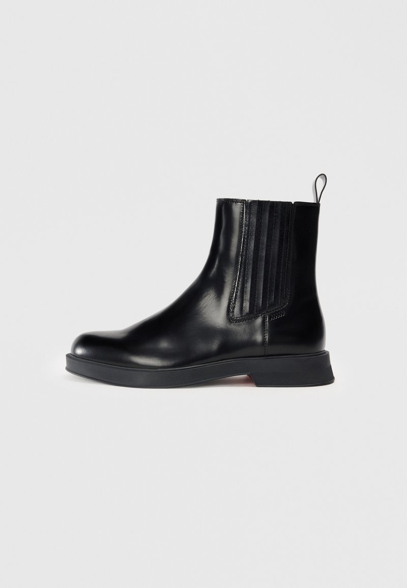 Bottine en cuir noir avec panneau latéral élastique, languette à l’arrière, bout arrondi et semelle en caoutchouc plate.