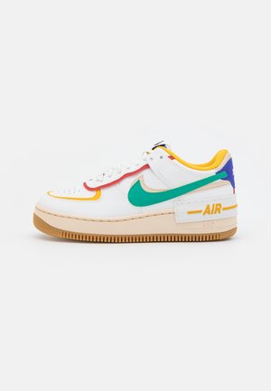 Sneakers bianche con accenti verdi, gialli, rossi e blu, suola in gomma e branding "AIR" sul lato, mostrate dal lato esterno.