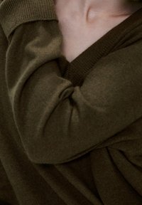 Olijfgroene trui met een v-hals ontwerp en een zachte textuur, voorzien van opgerolde mouwen en gathered stof voor een relaxte pasvorm.