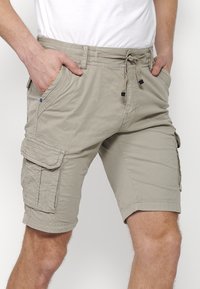 Khaki Cargo-Shorts mit verstellbarem Bund, zwei Seitentaschen und einer Cargo-Tasche am linken Bein. Aus leichtem Stoff gefertigt.