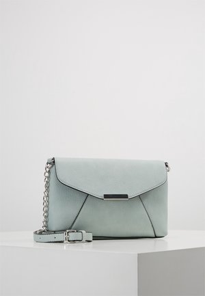 Lichtgrijze leren crossbodytas met zilveren kettingriem en rechthoekige metalen sluiting, rustend op een wit oppervlak tegen een effen achtergrond.