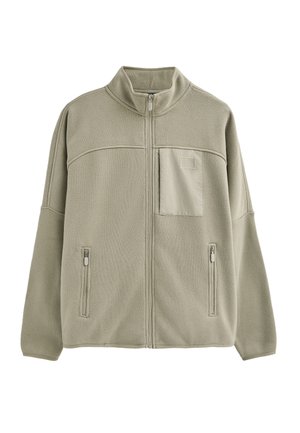 Hellgrüne Fleecejacke mit hohem Kragen, Frontreißverschluss und zwei seitlichen Taschen. Sie verfügt über eine horizontale Naht und eine kleine Pattentasche.