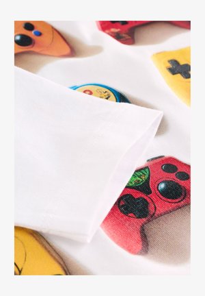 Tela blanca con estampados de mandos de videojuegos en colores naranja, amarillo, rojo y azul. Costuras finas visibles en el borde de la manga.