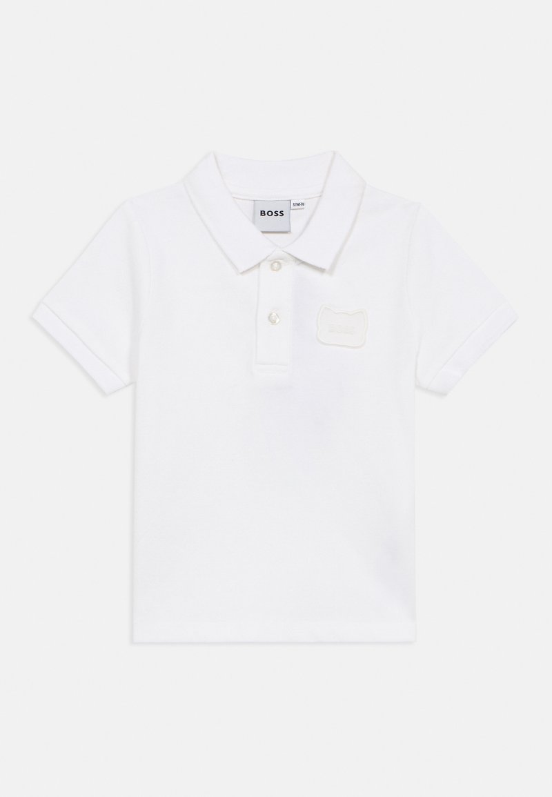 Polo blanco de algodón con manga corta, cuello clásico, tapeta de tres botones y un parche de logo texturizado en el pecho.