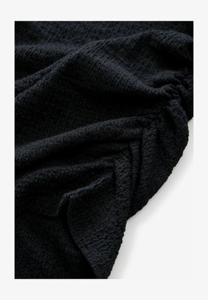 Textuur van zwart stof gedrapeerd, met een gekreukte oppervlakte en een zachte, pluche uitstraling met een subtiel, ongelijk patroon doorheen.