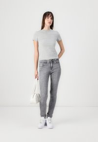 Gray fitted t-shirt, light gray skinny jeans, white sneakers, and a white handbag. Smooth fabric, casual design, slim silhouette, and simple accents.