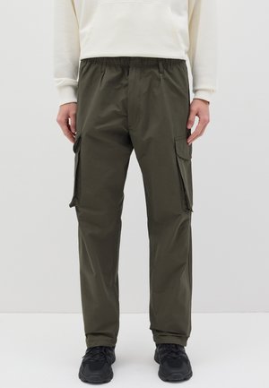 Pantaloni cargo verde oliva realizzati in tessuto leggero, con vita elasticizzata e due tasche laterali, abbinati a sneaker nere.