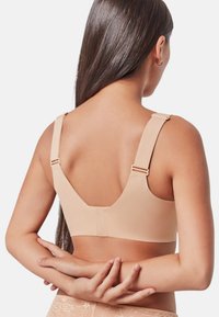 Sujetador nude sin costuras con tirantes ajustables y un diseño suave. Cuenta con una banda ancha y hardware mínimo para una sensación ligera.