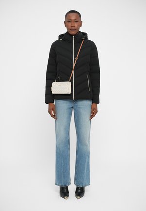 Black puffer jacket with chevron pattern, two front zip pockets, paired with light blue flared jeans and black pointed-toe boots. Gold-accented crossbody bag.