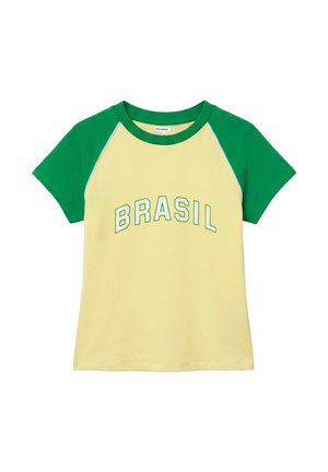 Tricou cu mâneci scurte, cu mâneci și guler verzi, corp galben deschis și „BRASIL” imprimat cu litere verzi pe piept.