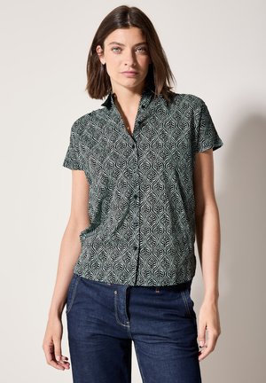 Kortetermijn zwart-wit patroon shirt met een bladdesign, een puntige kraag en een losse pasvorm. Gepaard met donkere jeans.