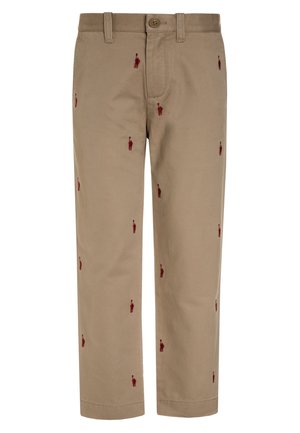 Pantalones de algodón beige con figuras bordadas en rojo distribuidas por la tela. Diseño clásico con cierre de botón y bolsillos laterales.