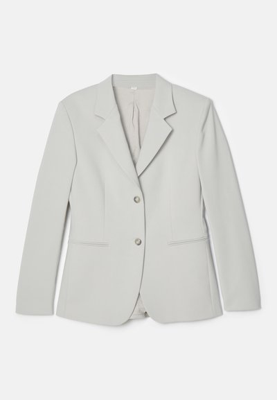 Šviesiai pilkas blazeriukas, pagamintas iš lygaus audinio, su įpjovimais ant apykaklės, dviejų mygtukų uždarymu ir dviem priekinių kišenių subtiliais akcentais.