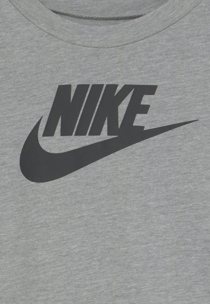 Schwarzes Nike-Logo mit Swoosh auf grauem Stoff, zentriert im Brustbereich eines T-Shirts.