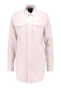 Camicia lunga rosa chiaro con bottoni frontali, colletto a punta e due tasche sul petto. Tessuto morbido e vestibilità rilassata.
