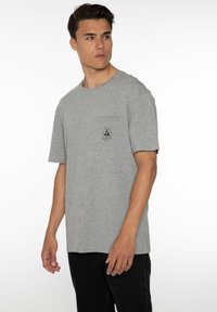 Grijze korte mouwen t-shirt gemaakt van een katoenmix met een ronde halslijn, voorzien van een borstzak en een grafisch logoontwerp.