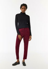 Czarny sweter z golfem w połączeniu z bordowymi spodniami o tapered i czarnymi loafersami, charakteryzujący się gładką fakturą i minimalistycznym designem.