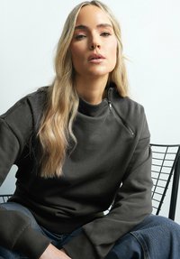 Mörkgrå sweatshirt med hög krage och dragkedja. Tillverkad av mjukt tyg, med ribbade muddar och avslappnad passform.