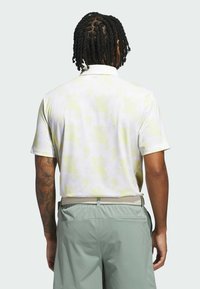 Short-sleeve polo in light yellow and white with a geometric pattern, made from breathable fabric; paired with light green shorts.