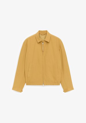 Lichtbruine jas met rits en kraag, lange mouwen, voorzakken en een elastische tailleband, plat neergelegd op een witte achtergrond.