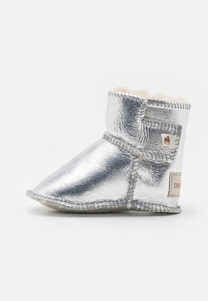 Srebrna metalna čizma s mekim unutrašnjim oblogom, zaobljenim prstom, ušivenim detaljima i etiketom sa strane. Fleksibilan, dizajn visine do gležnja.