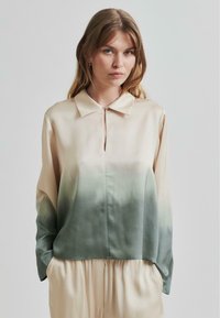 Blouse in satin con colletto, chiusura a bottoni e una sfumatura da beige chiaro a verde, con maniche lunghe e tasche laterali.