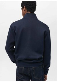 Felpa blu navy con colletto, caratterizzata da una texture morbida, maniche lunghe e vita aderente. Design minimalista, senza motivi o dettagli visibili.