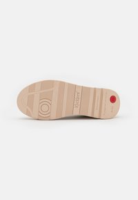 Sole di una scarpa beige con scanalature verticali e orizzontali, caratterizzata da un accento circolare vicino al tallone e marchi del brand. Taglia 38 indicata.