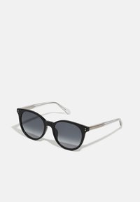 Lunettes de soleil noires avec une large monture angulaire et des verres gris dégradés. Les branches en argent présentent de subtils accents dorés.