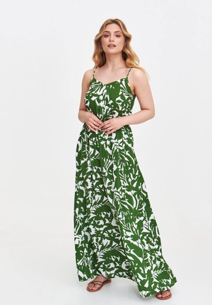 Grünes Maxikleid mit weißem Blattmuster, Spaghetti-Trägern und einer fließenden Silhouette. Der Stoff erscheint leicht und hat eine glatte Textur.