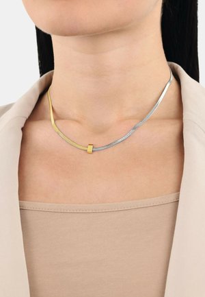 Gouden en zilveren ketting met een slank, gebogen ontwerp; bevat een gladde gouden accent en een zilveren ketting met gestructureerde secties.