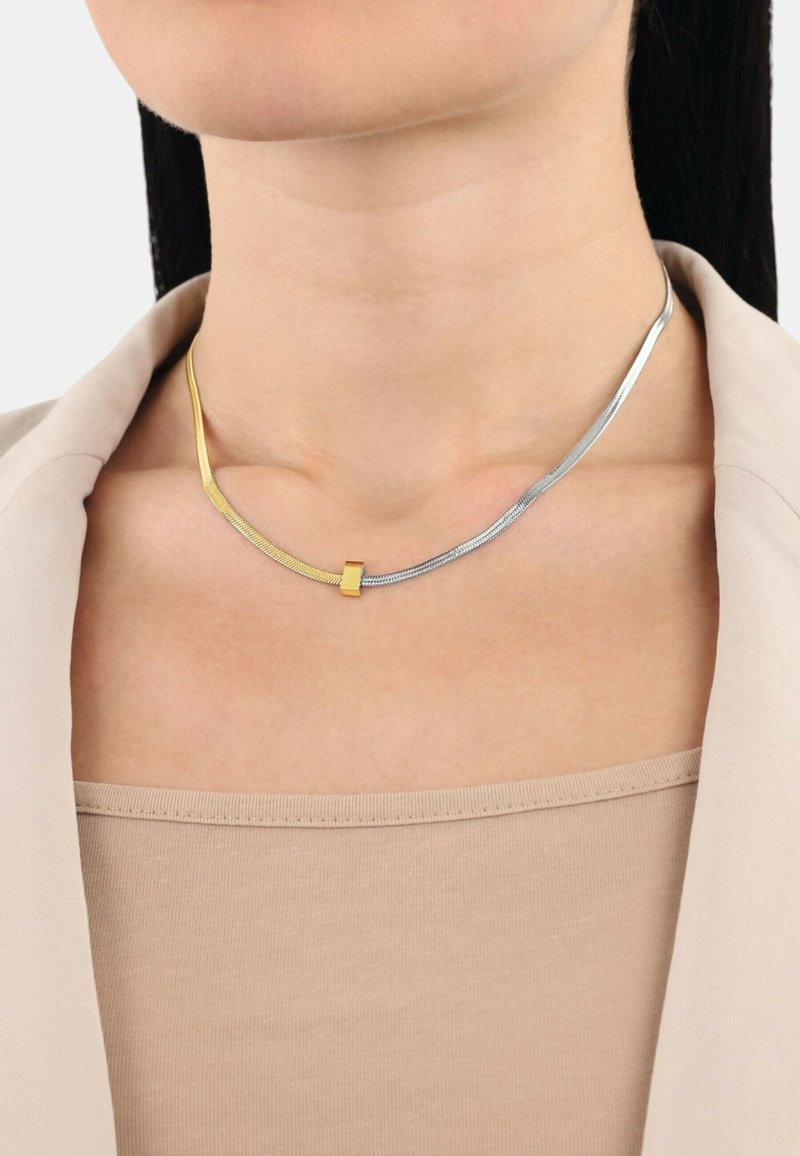 Collana in oro e argento con un design elegante e curvo; presenta un accento in oro levigato e una catena d'argento con sezioni testurizzate.