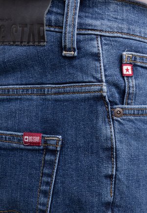Denim-Jeans Rückentaschenbereich mit rotem BIG STAR Aufnäher, Gürtelschlaufe, Metallniete und detaillierter oranger Naht auf blauem Stoff.