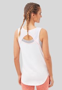 Camiseta atlética blanca sin mangas con un escote redondo y detalles recortados en la parte posterior, acentuada con un ribete de color rosa claro. Tejido suave con un ajuste ligeramente holgado.