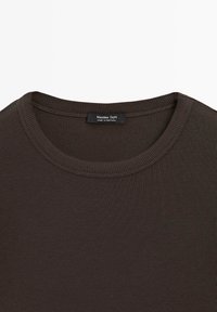 Hnědé žebrované tričko s kulatým výstřihem a hladkou texturou, s etiketou "Massimo Dutti", která uvádí, že je vyrobeno v Portugalsku.