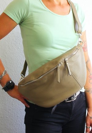 Olivgrüne Ledertasche mit geschwungenem Design, ausgestattet mit einem Reißverschluss und zwei Reißverschlusstaschen auf der Vorderseite. Verstellbarer Riemen mit metallischen Beschlägen.