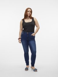 Black sleeveless bodysuit, high-waisted denim jeans, and blue heeled mules. The jeans feature a classic five-pocket design.