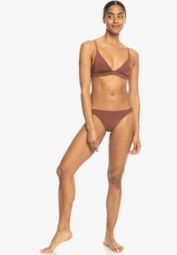 Čokoladno rjavi bikini s trokutastim vrhom in nizkimi hlačkami. Mehka, gladka tkanina z ozkimi naramnicami in minimalnim pokrivanjem.