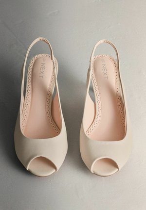 Beige open-toe slingback schoenen met een gladde afwerking, gegolfde rand rondom de binnenzool en een zachte binnenvoering.