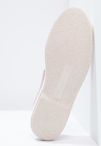 Suola di sneaker rosa chiaro con superficie in gomma testurizzata e marchio in rilievo. Il pannello laterale presenta un materiale in rete per la traspirabilità.