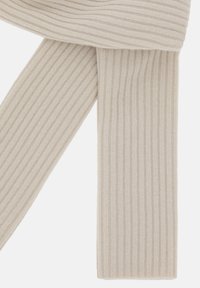 Beige ribbet tørklæde lavet af blødt strikmateriale, med lodrette striber og en flad kant, der giver et tekstureret udseende.