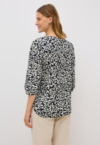 Flödande blus i mörk marinblått med ett vitt djurtryck, 3/4 ärmar och rundad nederkant. Lättviktig tyg med mjuk textur.