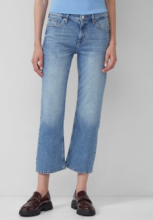 Lichtblauwe wijde jeans met een iets vervaagde afwerking, voorzien van vijf zakken en een knopenfly. Geselecteerd met donkerbruine instappers.