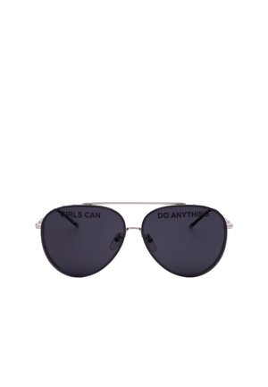 Occhiali da sole stile aviatore con lenti scure e sottili montature in metallo, con la scritta "LE RAGAZZE POSSONO FARE QUALSIASI COSA" sulle lenti.