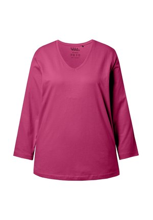 Haut à manches longues et col en V en coton rose vif. Texture douce, coupe décontractée, avec un ourlet légèrement courbé et une étiquette à l'intérieur du col.