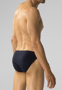 Granatowe kąpielówki o wzorzystym designie z małymi kształtami. Wykonane z gładkiego materiału, mają dopasowany krój i niską talię.