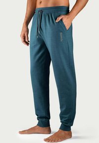 Türkisfarbene Jogginghosen mit einem Kordelzugbund, seitlichen Taschen, schmal zulaufenden Bündchen und dem Logo "Bench." in einer helleren Farbe auf dem Bein.