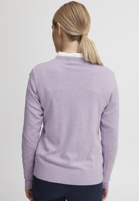 Pull en lilas tricoté avec des manches longues, un col rond et un ourlet côtelé. Le matériau semble doux et léger, avec une texture lisse.