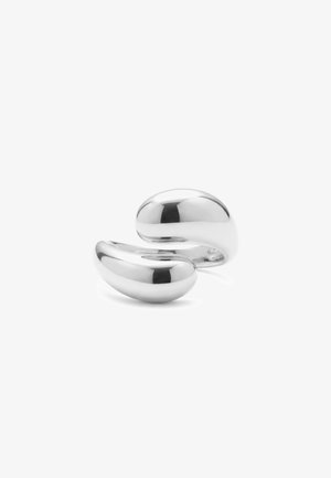 Anneau en argent lisse et poli avec un design moderne, incurvé et ouvert reposant sur une surface blanche.
